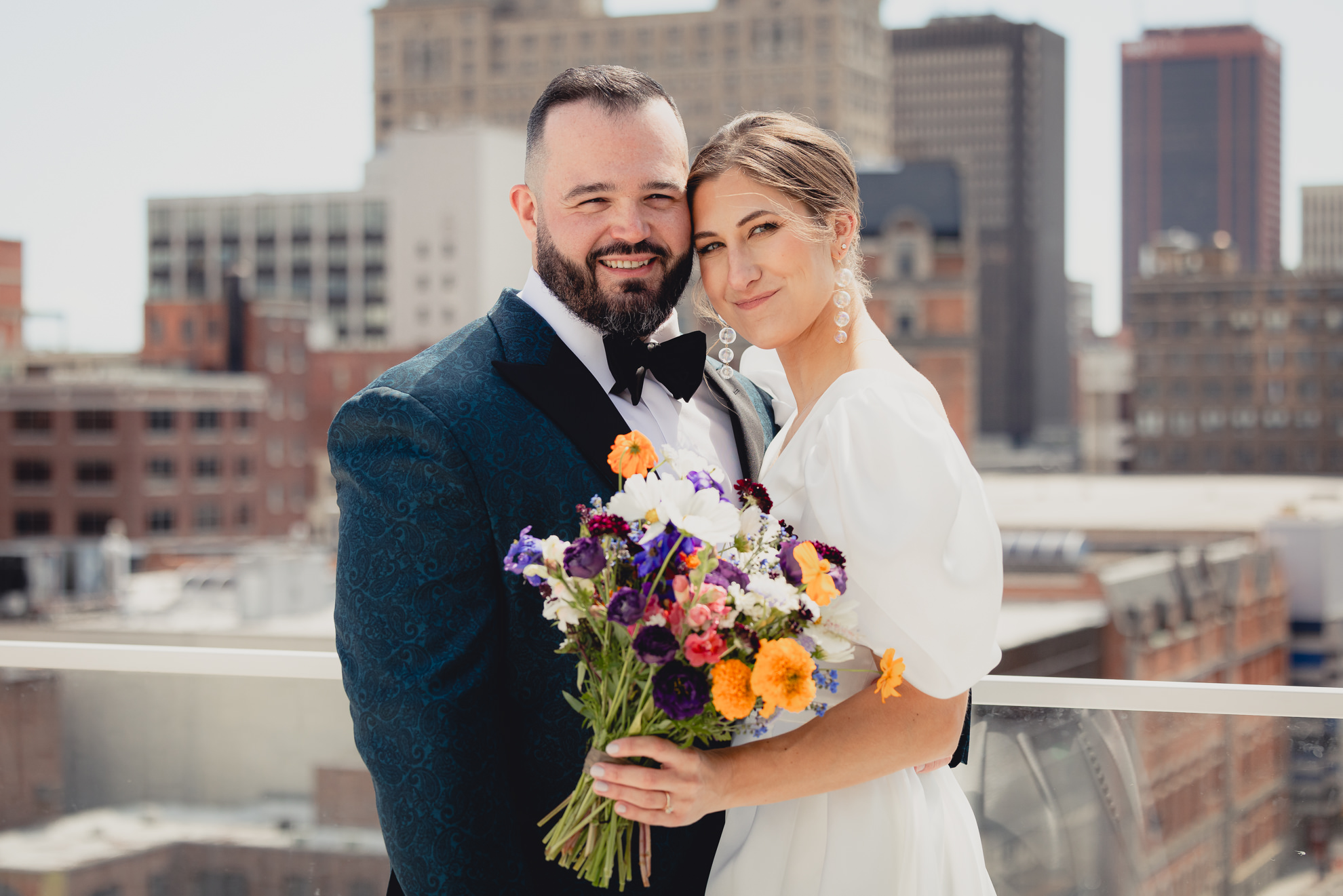 bride and groom smile for camera with skyline in background before wedding at Vue on the roof of the Curtiss Hotel in Buffalo, NY