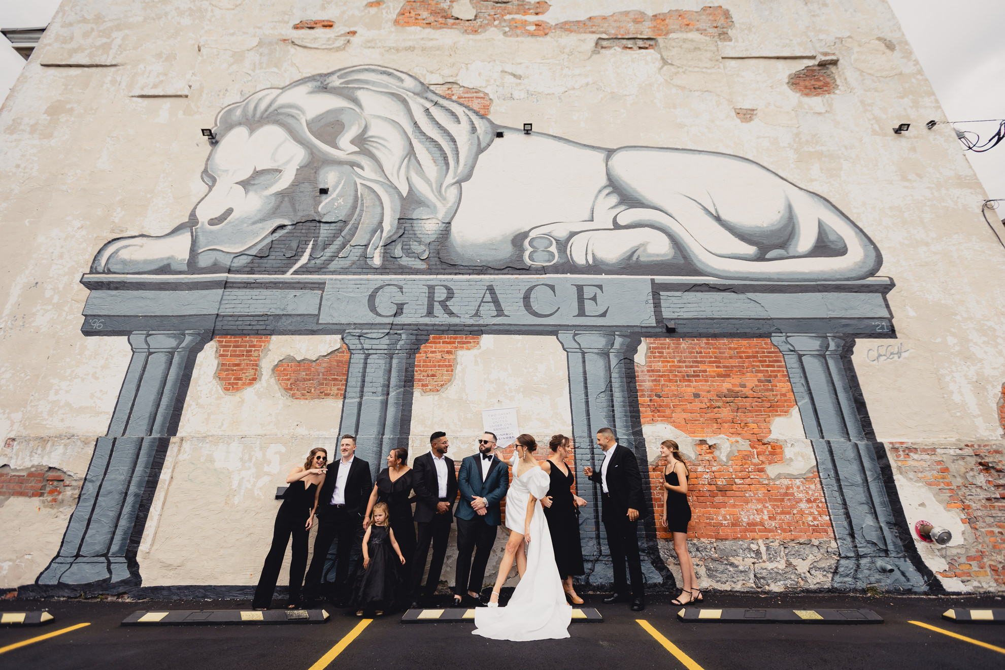 wedding party poses in front of lion mural on Delaware Ave. in Buffalo, NY