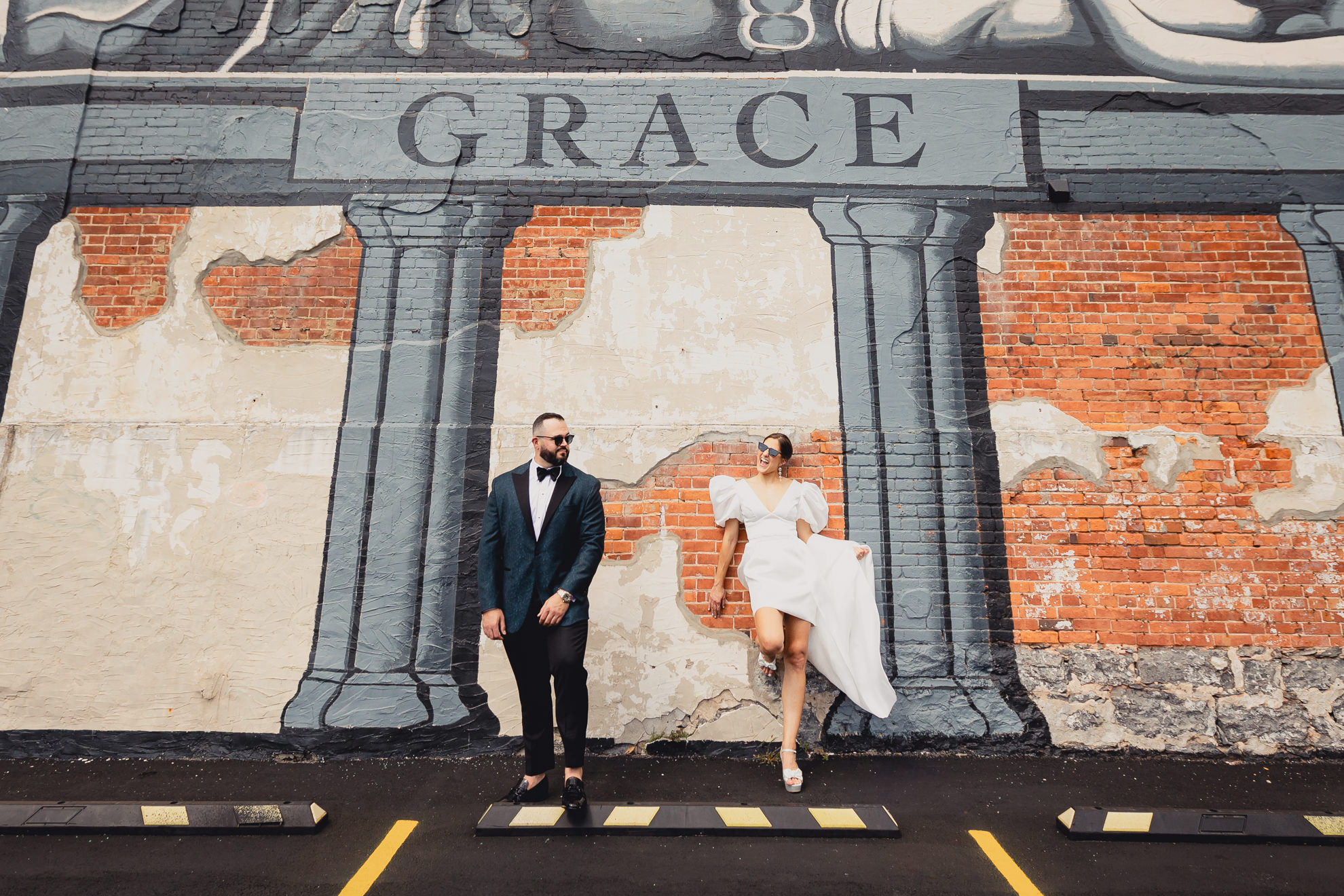 bride and groom pose in front of lion mural on Delaware Ave. in Buffalo, NY