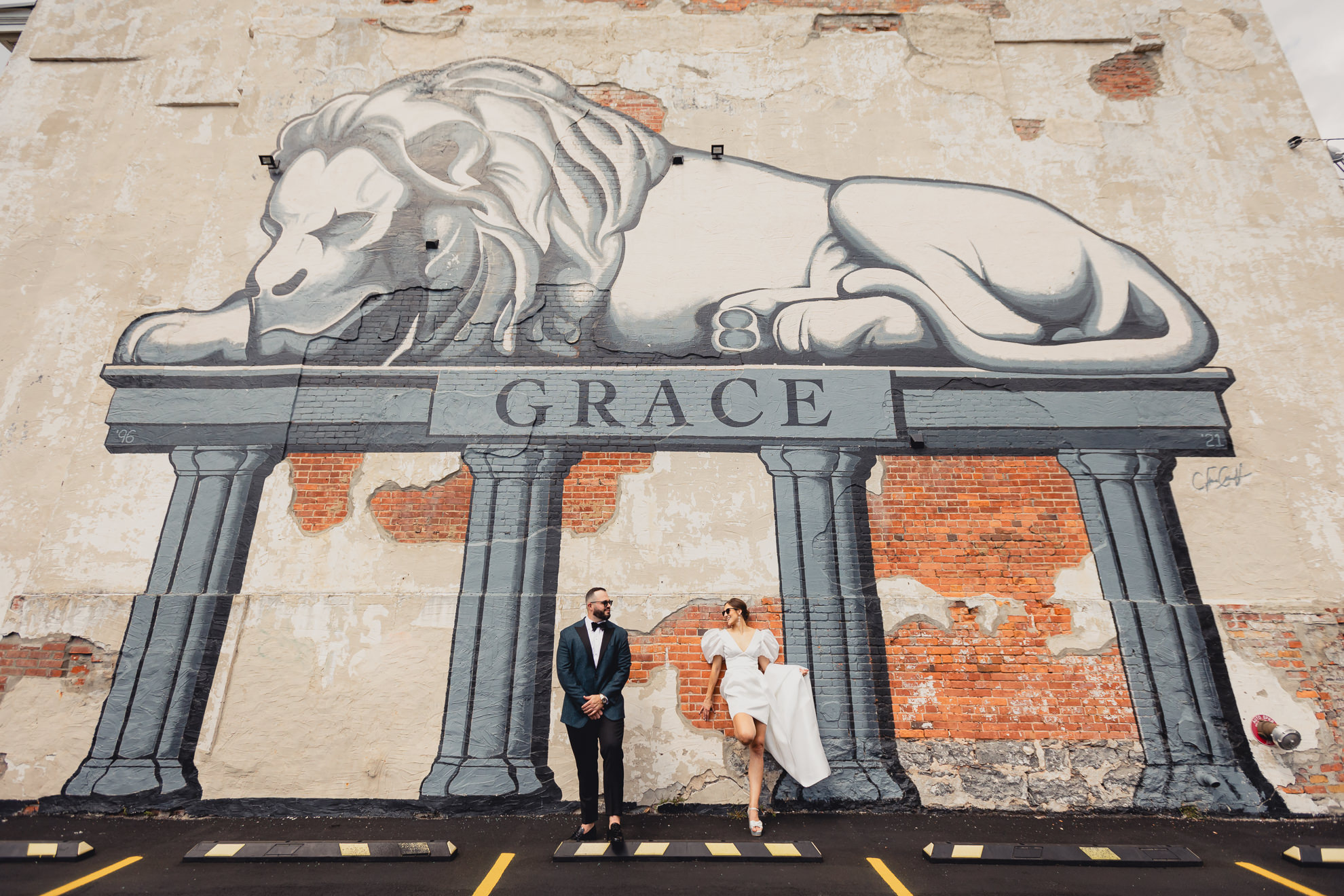 bride and groom pose in front of lion mural on Delaware Ave. in Buffalo, NY