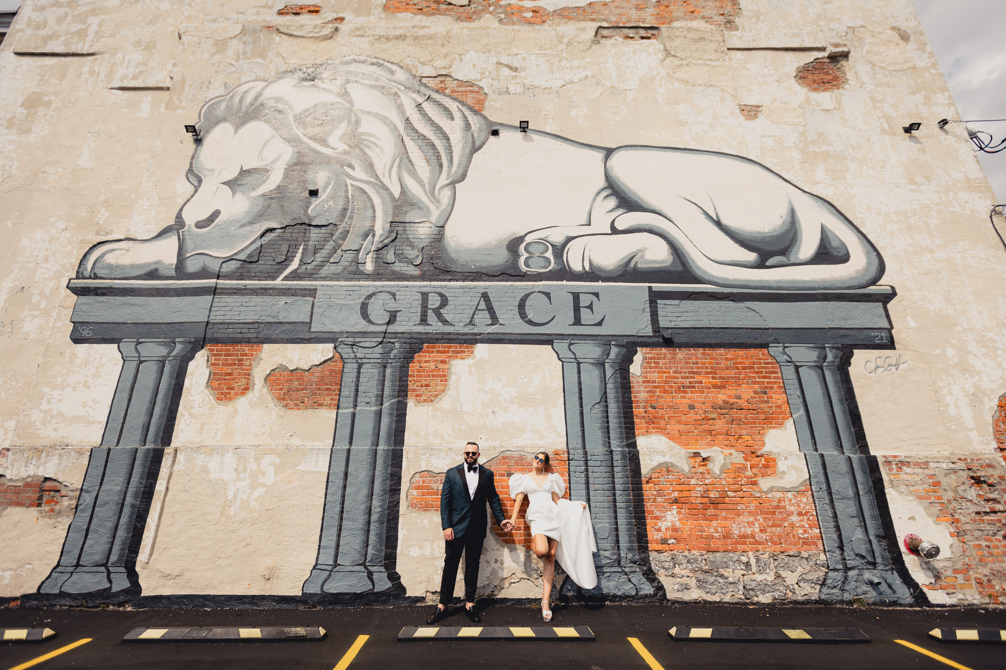 bride and groom pose in front of lion mural on Delaware Ave. in Buffalo, NY