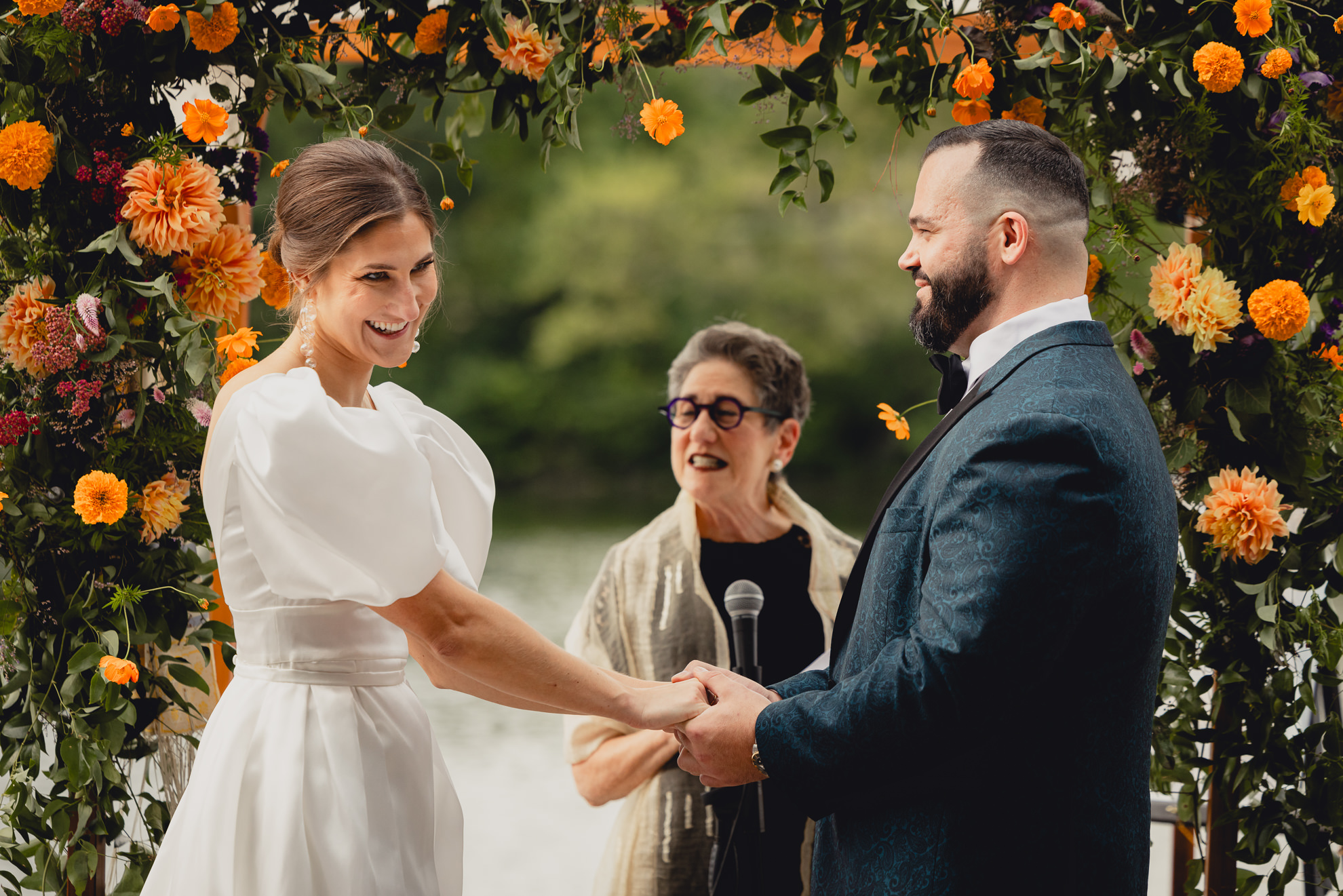 bride and groom hold hands and laugh together during wedding ceremony at Hoyt Lake at the Terrace at Marcy Casino in Buffalo, NY