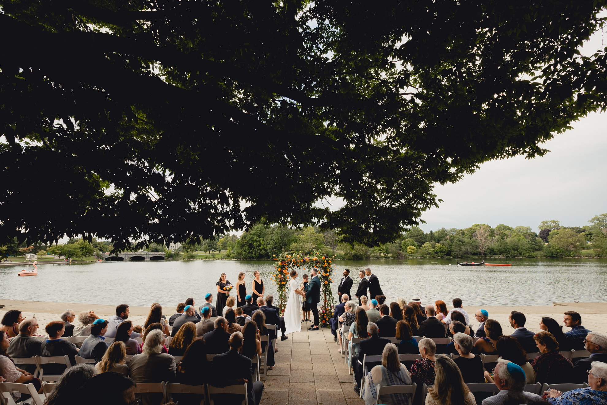 bride and groom hold hands during wedding ceremony at Hoyt Lake at the Terrace at Marcy Casino in Buffalo, NY