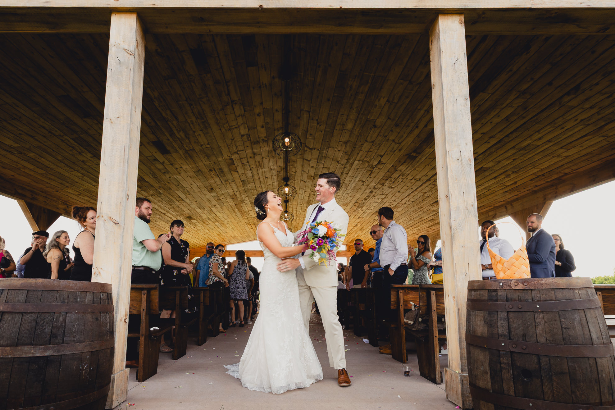 bride and groom laugh while walking up aisle during wedding ceremony at The Gallagher Barn in Medina, NY