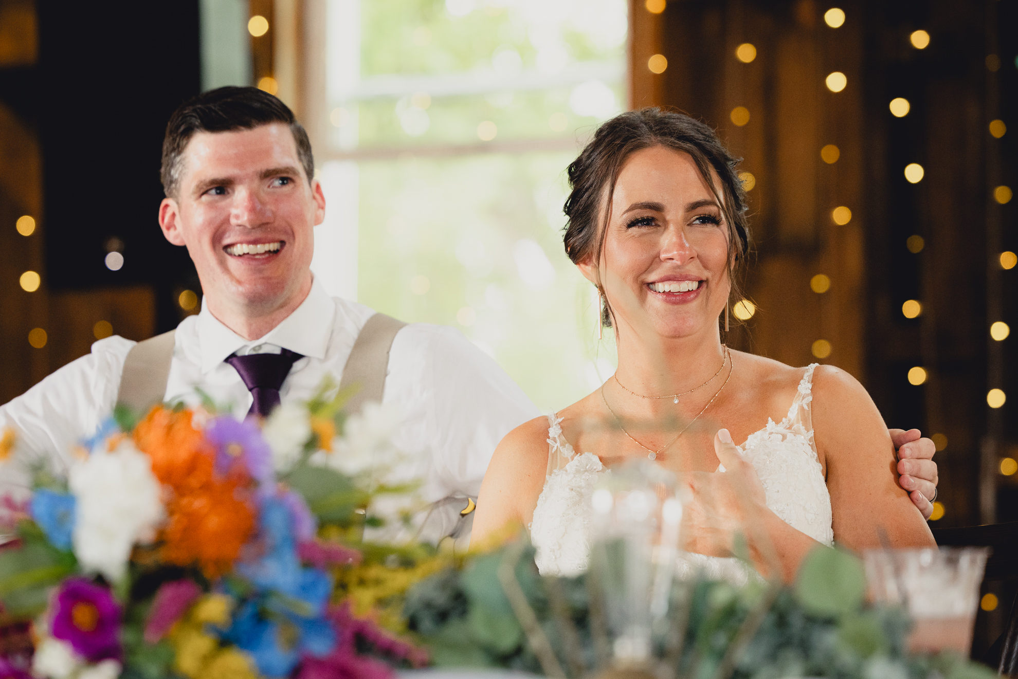 bride and groom laugh during speeches during wedding reception at The Gallagher Barn in Medina, NY