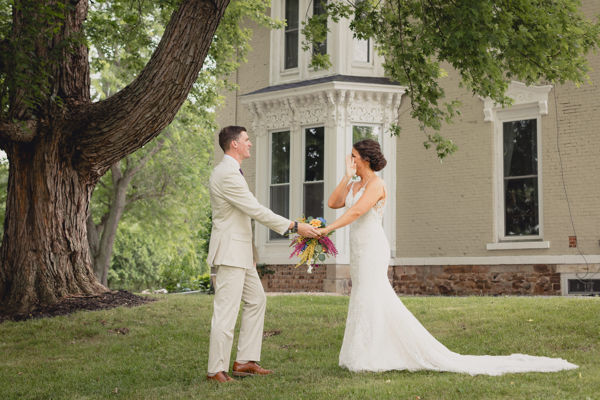 bride wipes tear after first look outside historic house at The Gallagher Barn in Medina, NY