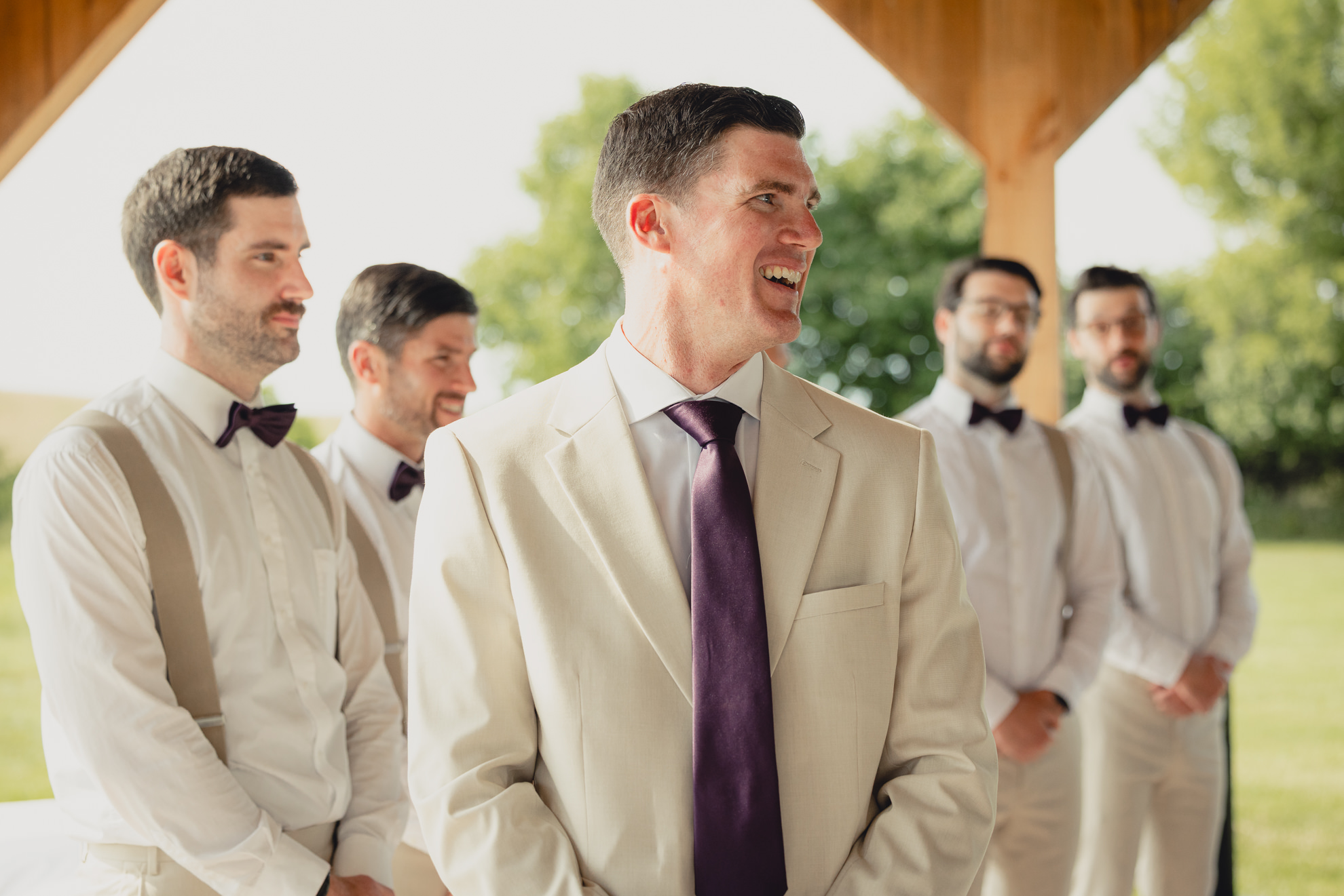 groom smiles at bride coming down aisle during wedding ceremony at The Gallagher Barn in Medina, NY