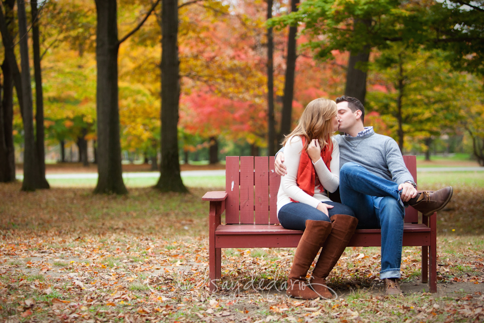 couple kisses on bench in Chestnut Ridge Park during their engagement portrait photo in Orchard Park, NY