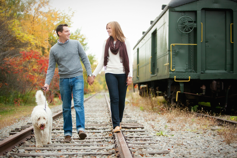 couple balances as they walk on train tracks during the fall during engagement session near Buffalo, NY