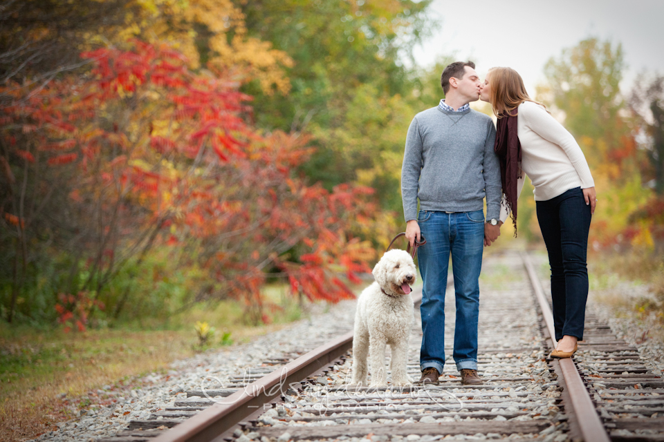 couple kisses on train tracks during the fall during engagement session near Buffalo, NY