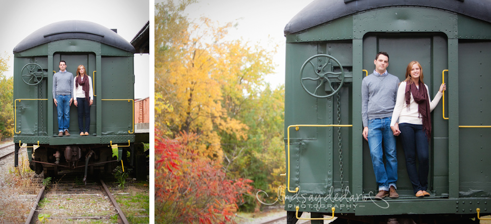couple stands on train during the fall while posing for photographer during engagement session near Buffalo, NY
