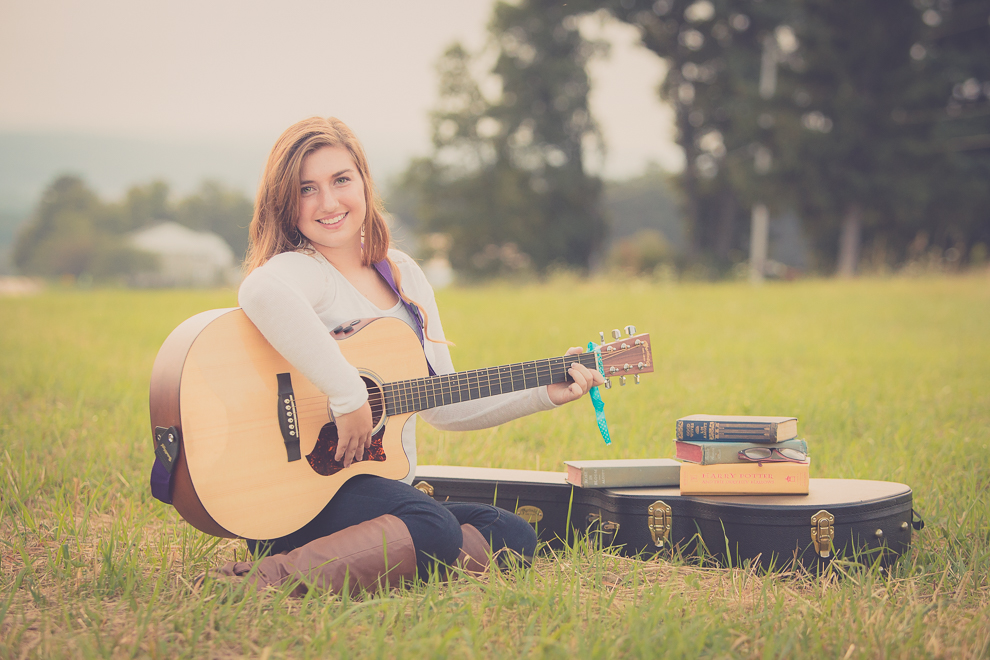 senior portrait photography of young woman posing for photographer with guitar in field in Bemus Point, NY, a town near Buffalo 