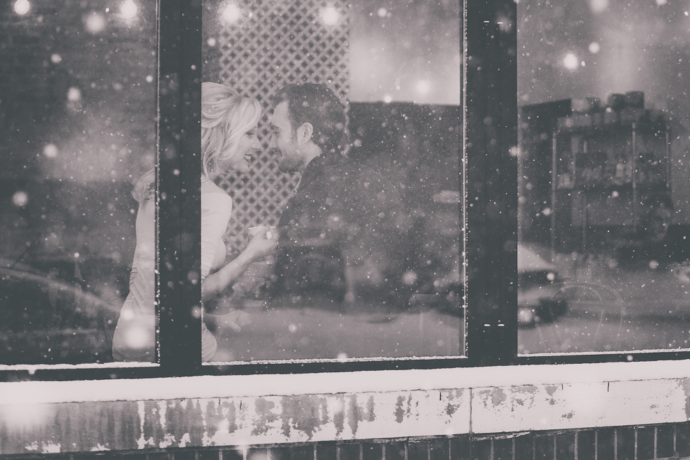 wedding engagement photography of couple inside snowy window of coffee shop, Tipico Coffee, in Buffalo, NY