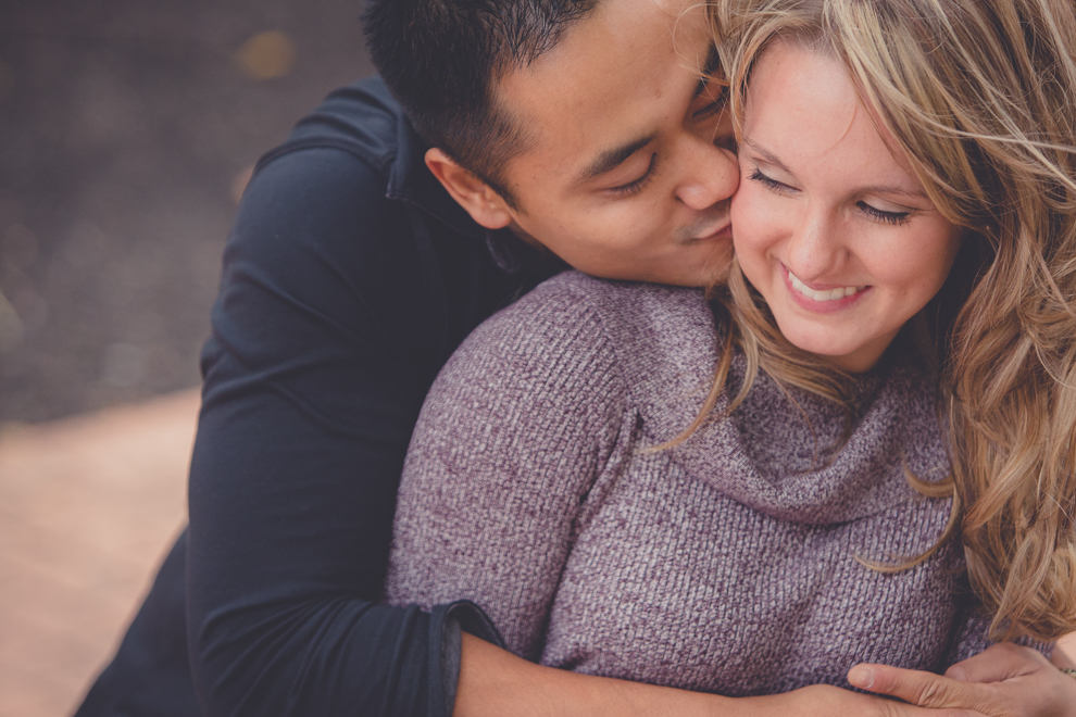 Two Niagara University Alumni kissing on bench during their wedding engagement photography session