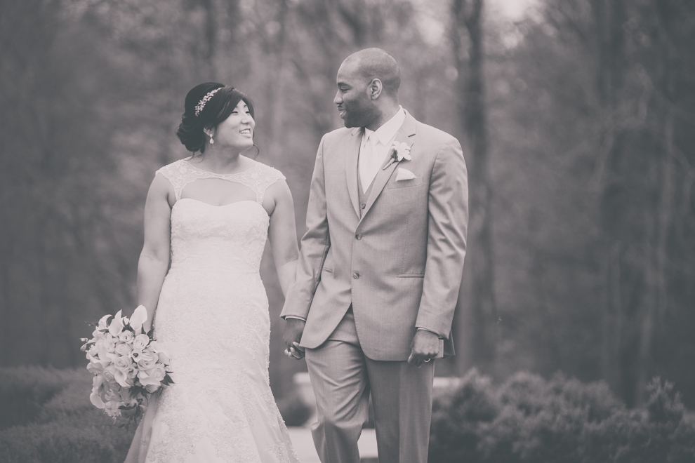 bride and groom hold hands in garden at outdoor wedding ceremony venue, the Avanti Mansion, near Buffalo, NY