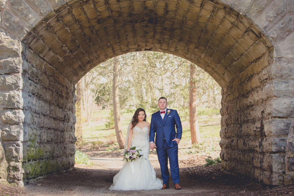 bride and groom hold hands beneath ivy bride at whimsical urban woodland themed wedding in buffalo, ny at webb lofts, lafayette hotel, pearl st brewery