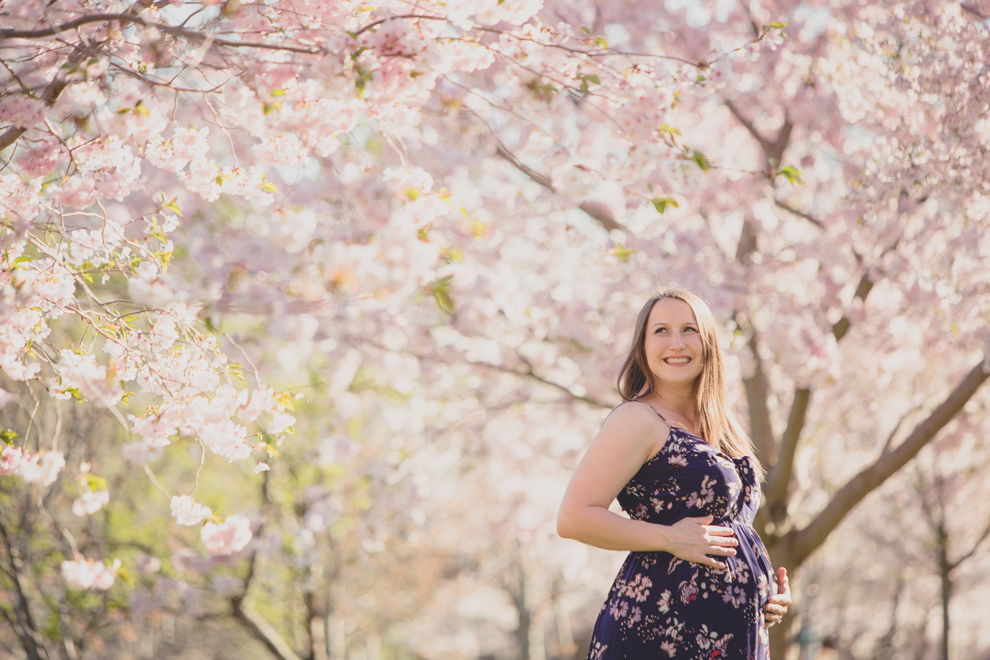 pregnant woman in whimsical spring floral maternity photography session at Delaware Park in Buffalo, NY with cherry blossom and magnolia trees