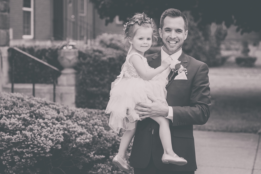 groom poses with flower girl during wedding at St. Joseph's University Parish Church in Buffalo, NY