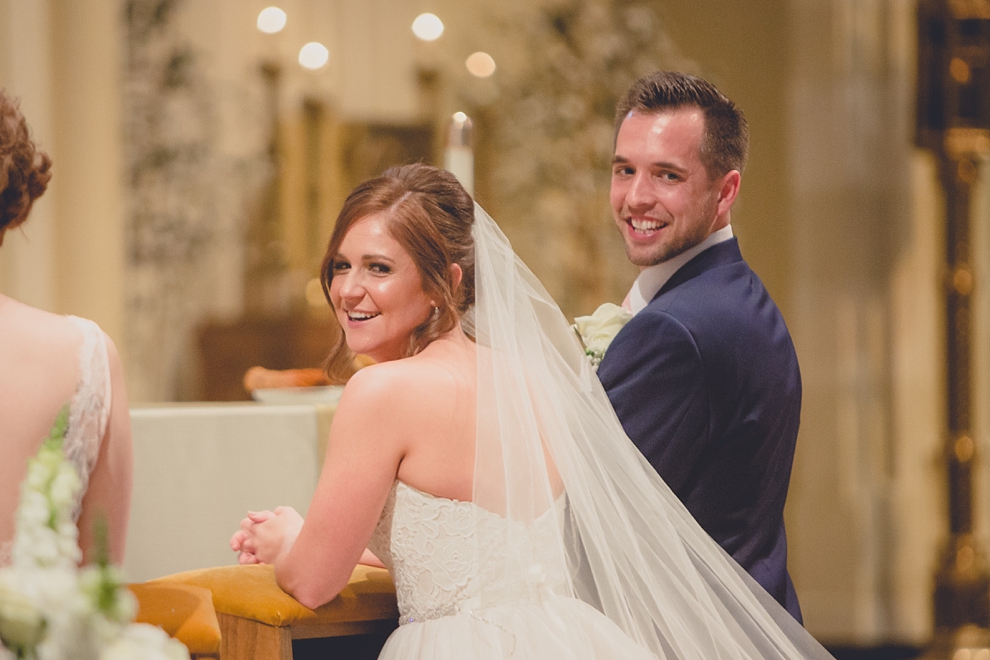 bride and groom smile at guests during wedding at St. Joseph's University Parish Church in Buffalo, NY