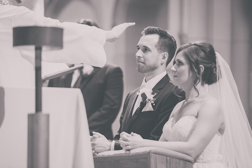 priest blesses bride and groom during wedding at St. Joseph's University Parish Church in Buffalo, NY