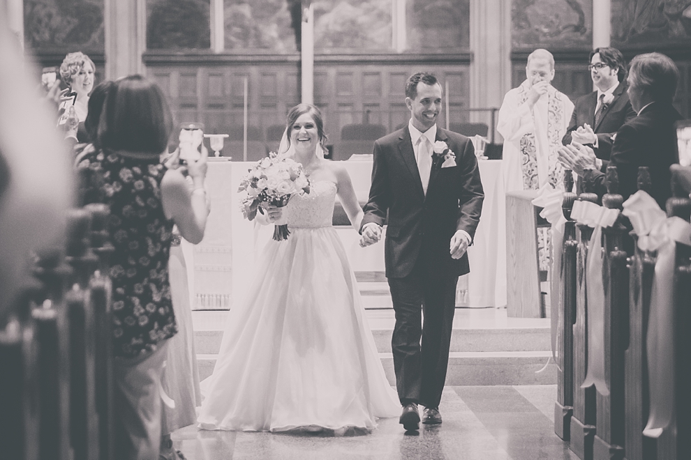 bride and groom walk down aisle during wedding at St. Joseph's University Parish Church in Buffalo, NY