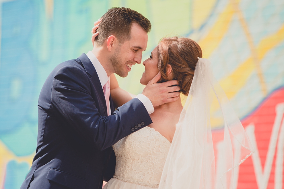 bride and groom pose for portrait near "greetings from Buffalo" mural in downtown Buffalo, NY