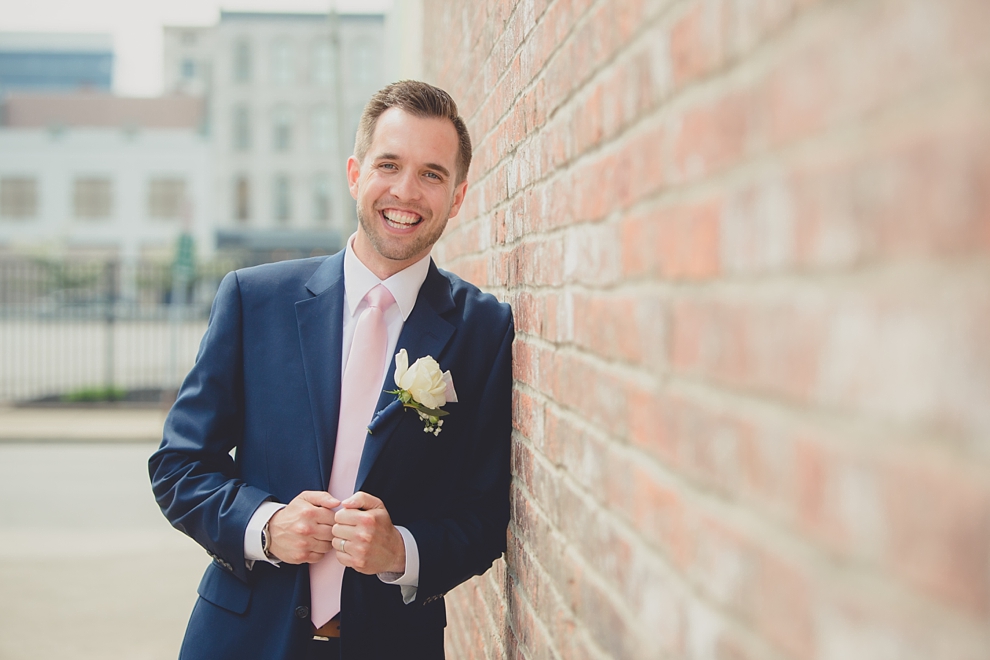 groom poses for portrait near "greetings from Buffalo" mural in downtown Buffalo, NY