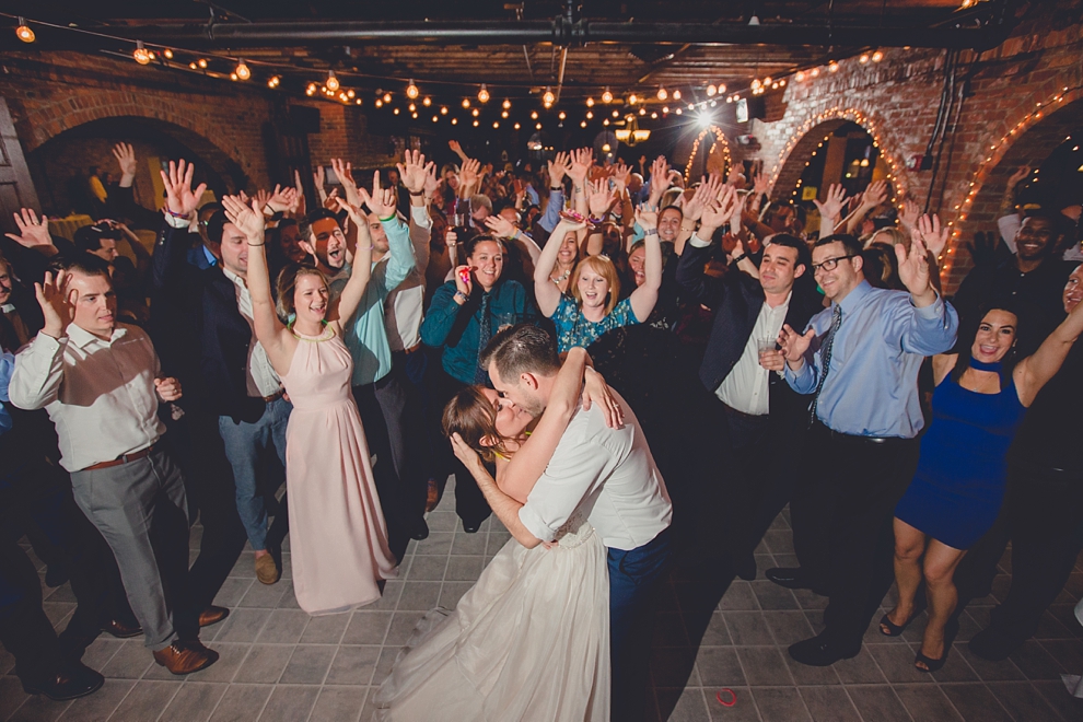 bride and groom kiss in front of cheering guests on dance floor at wedding at Pearl Street Grill and Brewery in Buffalo, NY