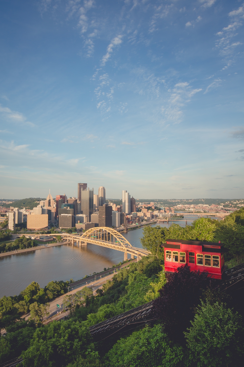 wedding engagement photography of couple snuggling in the back of the Pittsburgh Incline with the skyline in the background