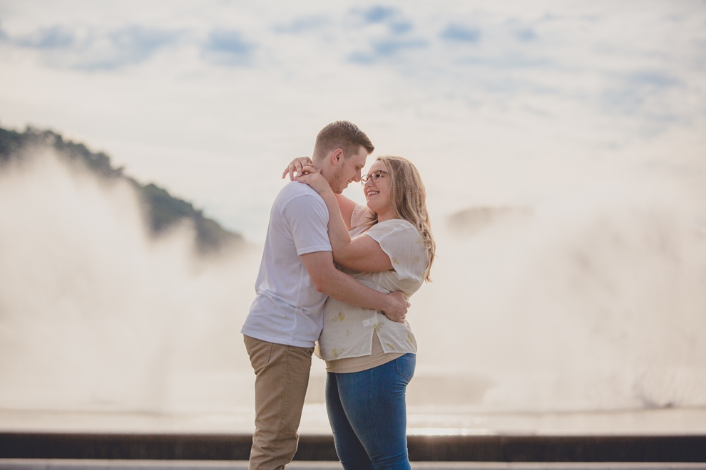 engagement photography of couple holding hands and looking at each other with fountain behind them in Point Park in Pittsburgh