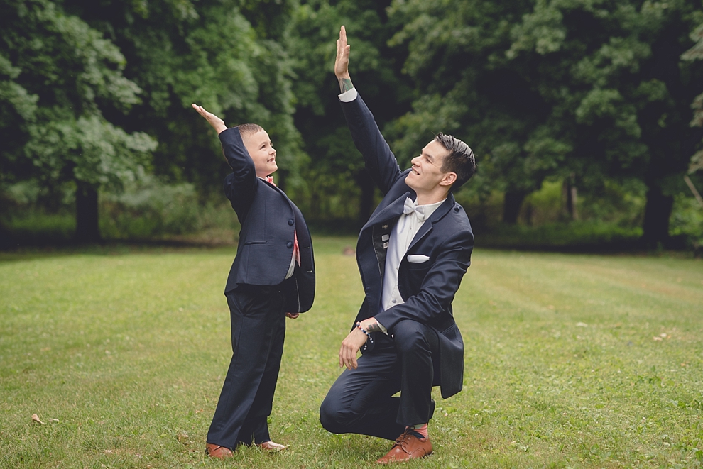 groom high-fiving ring bearer before garden wedding ceremony at Samuel's Grande Manor near Buffalo, NY