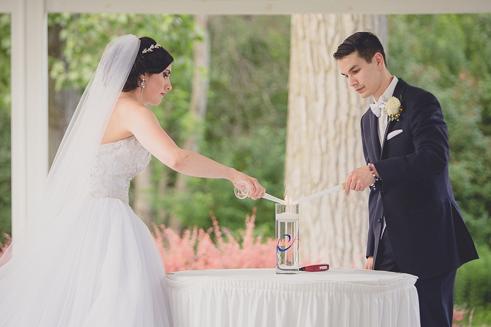 bride and groom light candle during garden wedding ceremony at Samuel's Grande Manor near Buffalo, NY