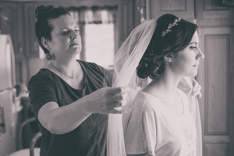 photography of bride getting veil adjusted by Lizzy Dugan of Salon Elizabeth before garden wedding ceremony at Samuel's Grande Manor near Buffalo, NY