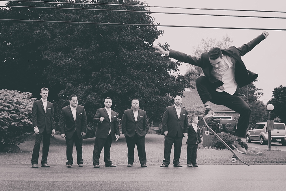groom skateboarding past groomsmen before garden wedding ceremony at Samuel's Grande Manor near Buffalo, NY