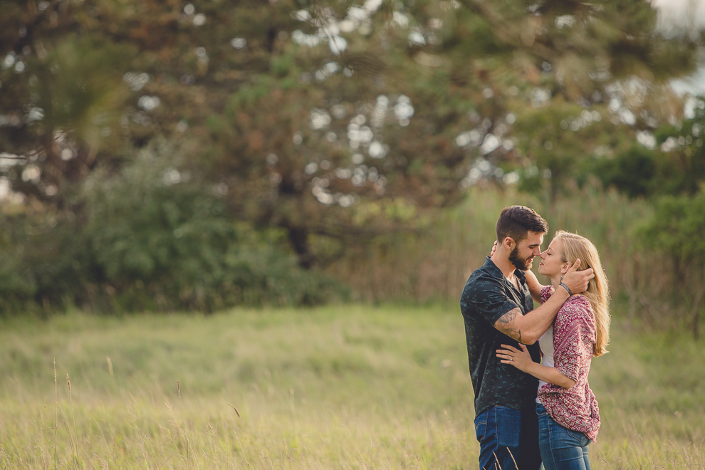 engagement photography of bride and groom about to kiss in front of pine trees in field at Tifft Nature Preserve in Buffalo, NY