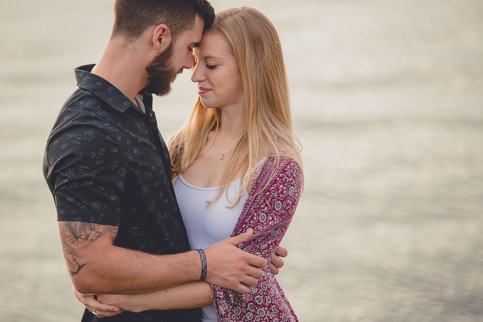 Bride and groom stand with their foreheads touching during wedding engagement photography session on Gallagher Beach at Buffalo Harbor State Park in Buffalo, NY