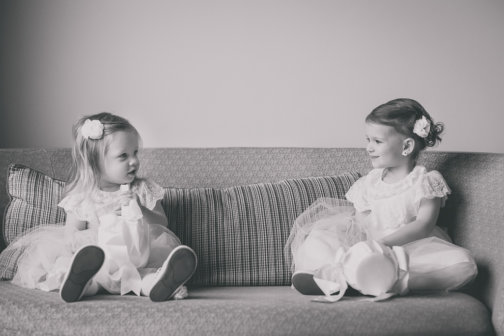 flower girls look at each other on couch before wedding at Marriott Hotel in Buffalo, NY