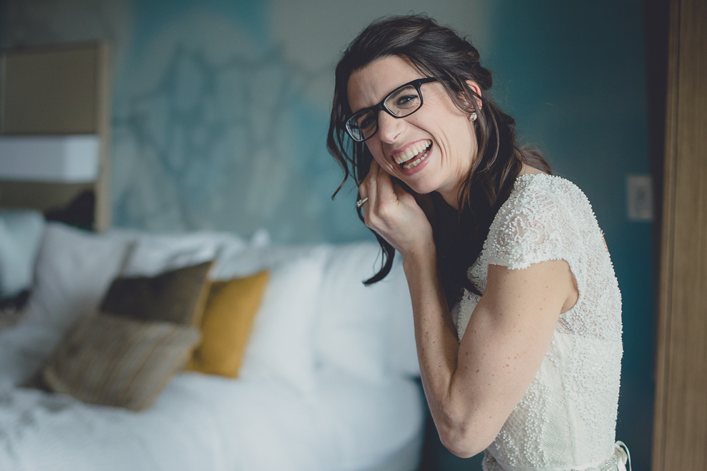 bride puts on earrings as she gets ready for wedding at Marriott Hotel in Buffalo, NY
