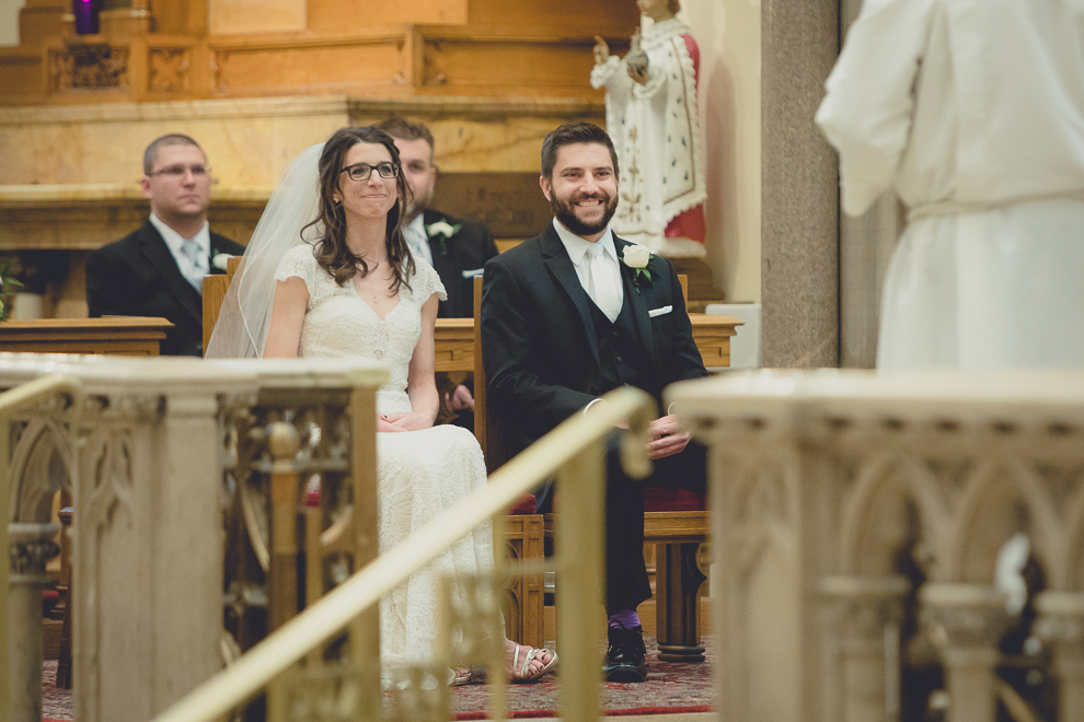 bride and groom listen to priest during wedding ceremony at St. Louis Church in Buffalo, NY