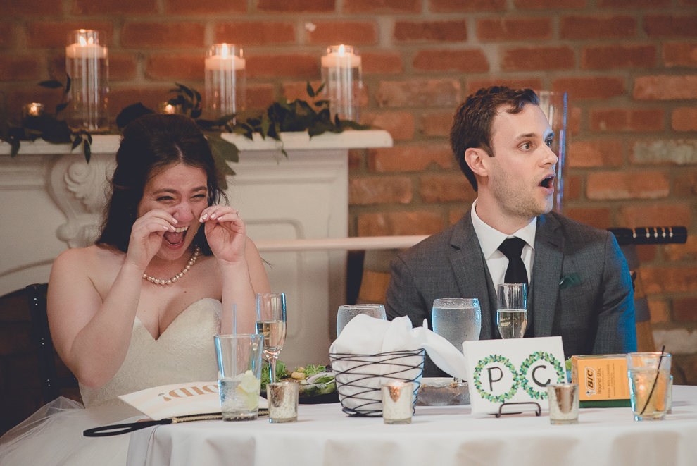 bride and groom laugh during maid of honor speech during wedding reception in Hotel Lafayette in Buffalo, NY