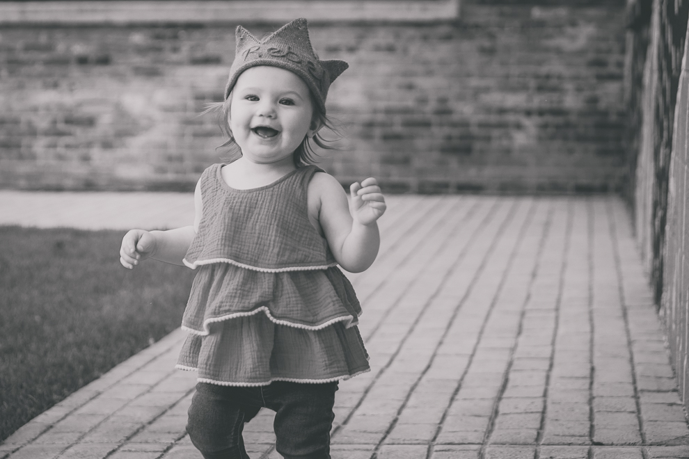 little girl smiles at photographer while running during family portrait photography session in front of murals on Chandler St. in Buffalo, NY