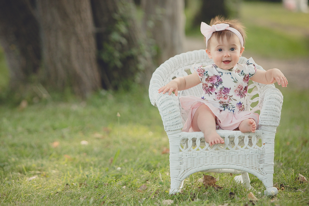 baby smiles for photographer during family portrait photography session in at Tifft Nature Preserve in Buffalo, NY