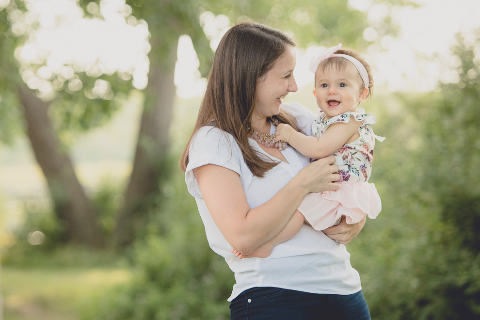 mom looks at baby smiling for photographer during family portrait photography session in at Tifft Nature Preserve in Buffalo, NY