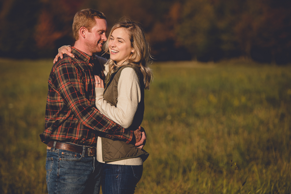 bride and groom laugh in field during wedding engagement photos among fall foliage at their property in Ellicottville, NY