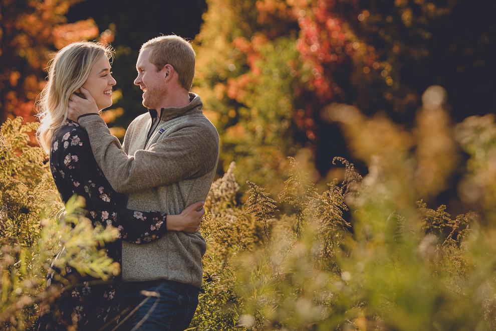 bride and groom laugh in field during wedding engagement photos among fall foliage at their property in Ellicottville, NY