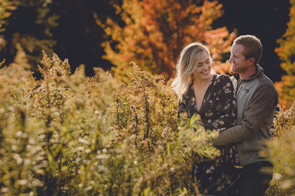 bride and groom laugh in field during wedding engagement photos among fall foliage at their property in Ellicottville, NY
