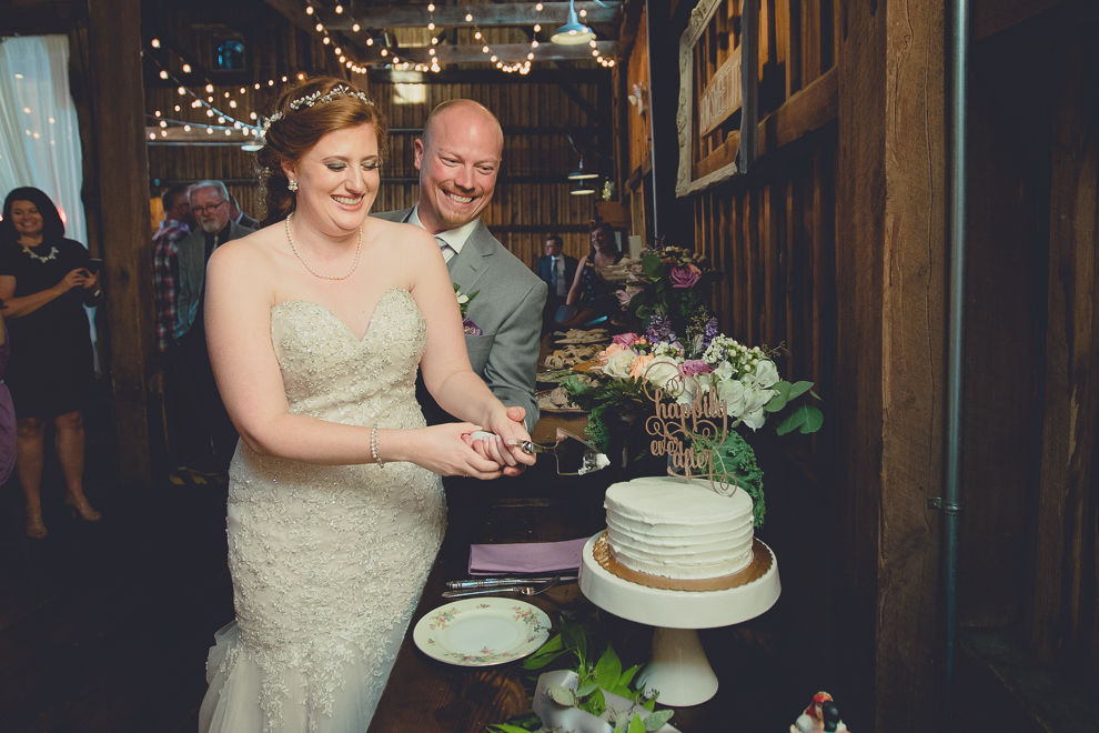 bride and groom cut cake at wedding reception in barn at a Hayloft in the Grove in East Aurora, near Buffalo, NY