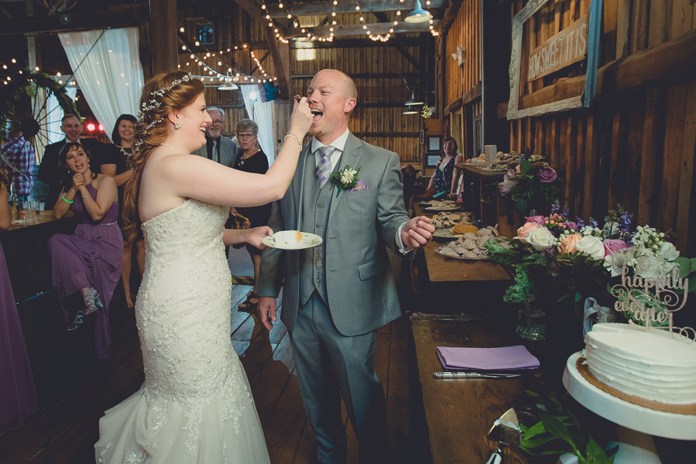bride and groom cut cake at wedding reception in barn at a Hayloft in the Grove in East Aurora, near Buffalo, NY