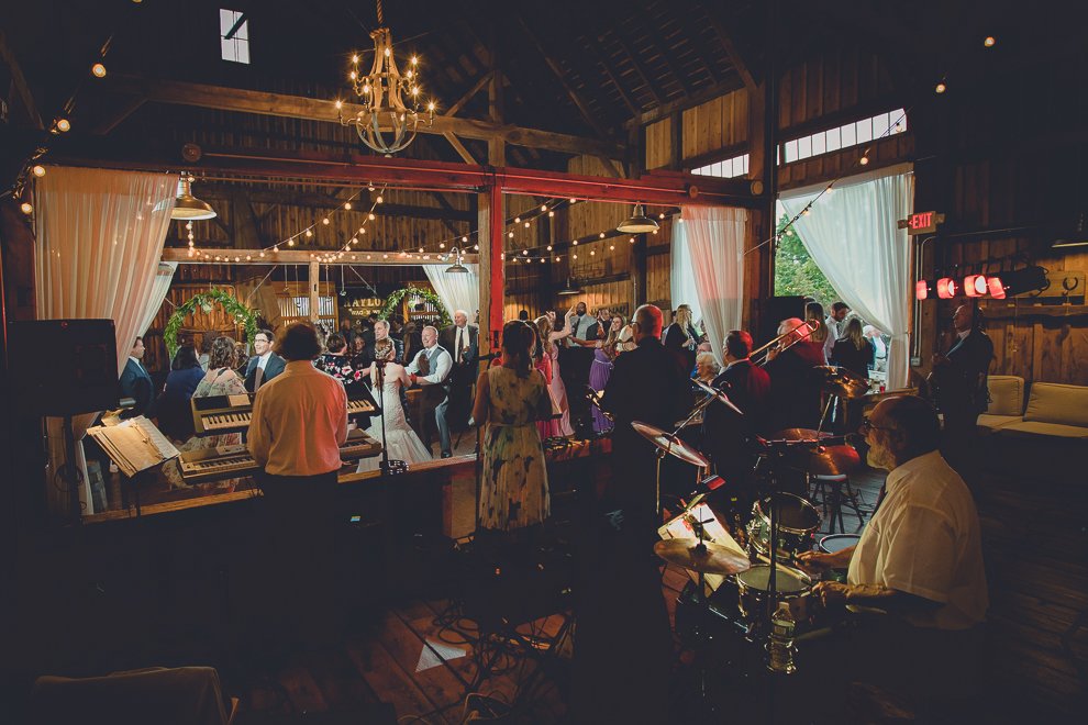 guests dance in front of band at wedding reception in barn at a Hayloft in the Grove in East Aurora, near Buffalo, NY