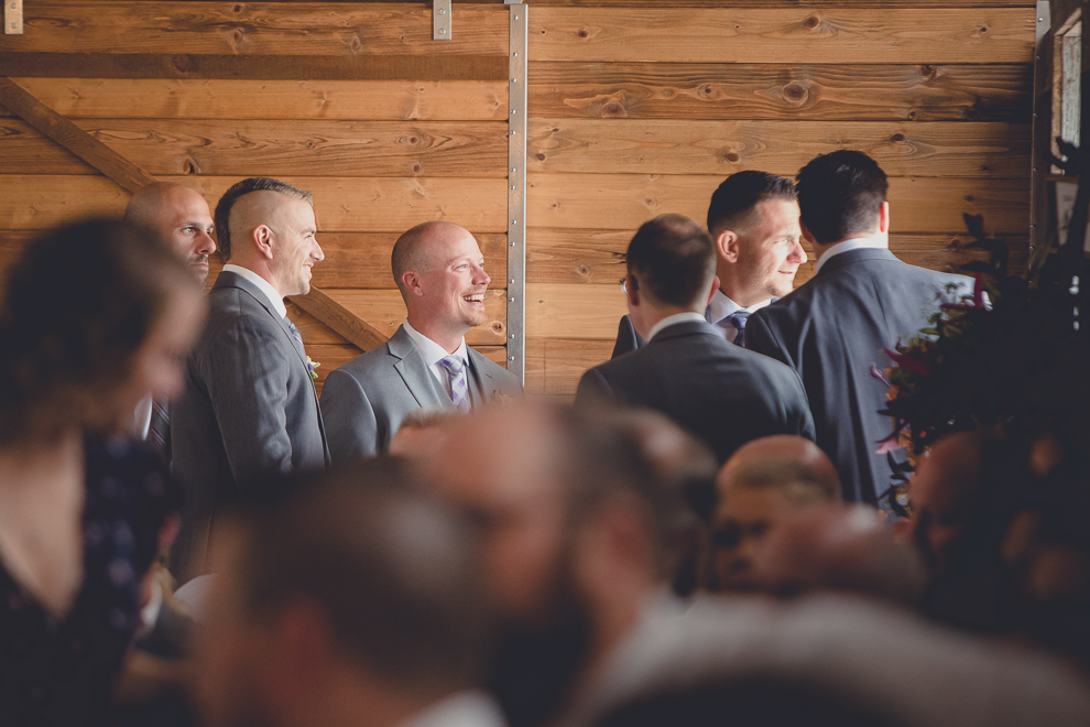 groom laughing at wedding ceremony in converted stables at a Hayloft in the Grove wedding in East Aurora, near Buffalo, NY